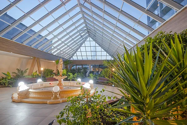 Das Bild zeigt den begrünten Innenbereich mit Brunnen im Hotel Olymp IV Spa & Wellness in Kolberg, Polen.