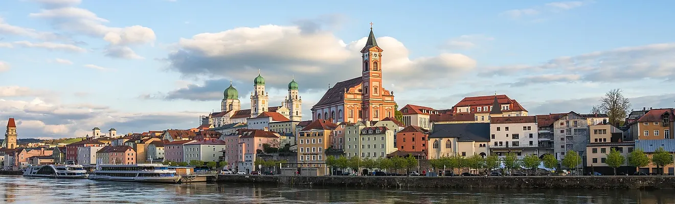 Das Bild zeigt einen Moment in der Dreiflüssestadt Passau, im Hintergrund sind der Stephansdom mit seinen charakteristischen grünen Kuppeln und die St. Paulskirche zu sehen.
