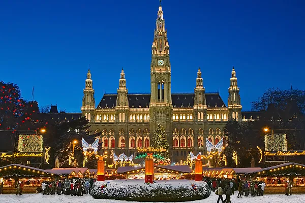 Das Bild zeigt den festlich beleuchteten Wiener Christkindlmarkt auf dem Rathausplatz in Wien vor dem historischen Rathaus