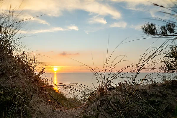 Bei dem Bild handelt es sich um eine malerische Aufnahme des Ostseestrands während eines Sonnenuntergangs