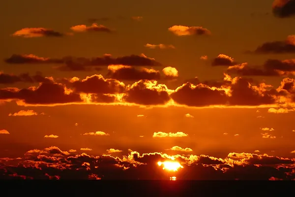 Dies ist eine Aufnahme eines Sonnenuntergangs in der Karibik, die die dramatische Farbgebung des Himmels und der Wolken zeigt